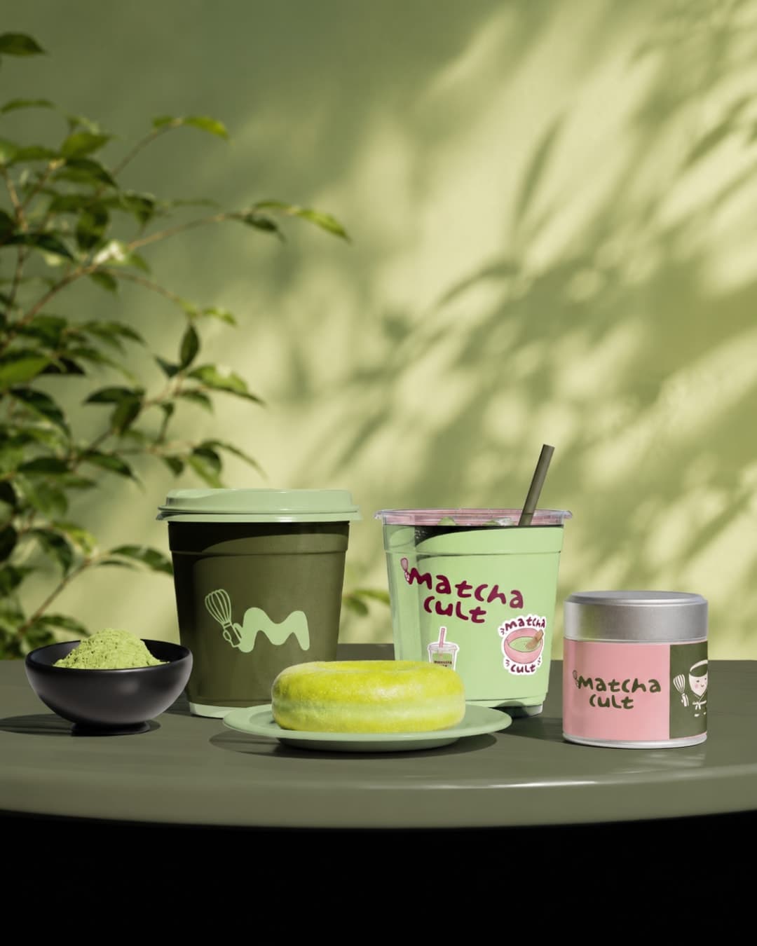 Cups, tins and a matcha cake laid out on a café table