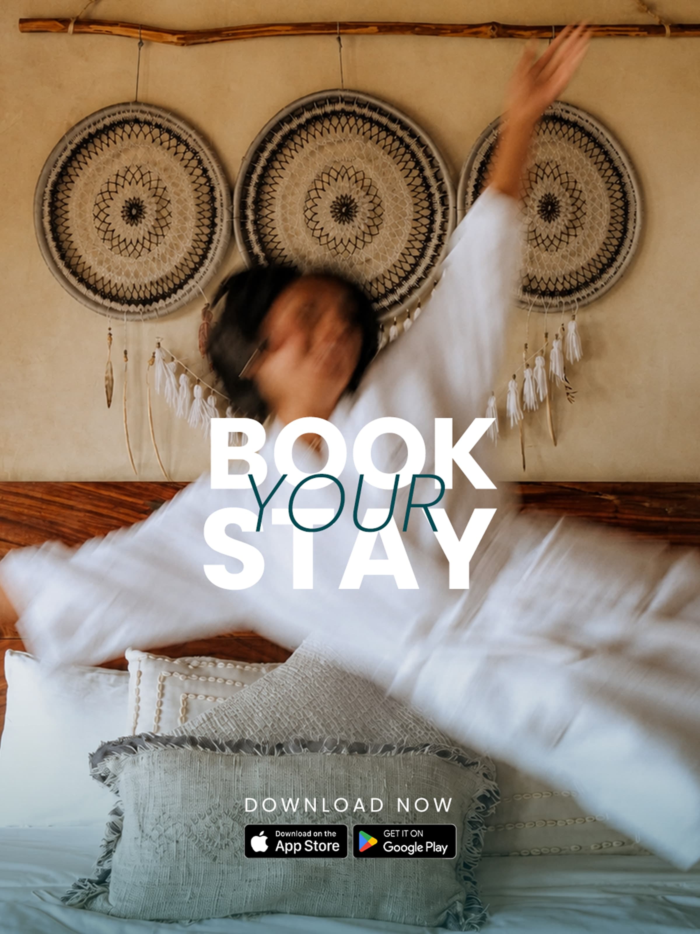 Book your stay — a guest sprawled on a bed beneath dreamcatchers